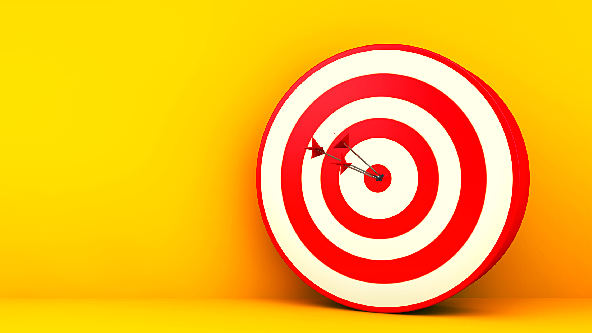 red and white target with arrow in bullseye against yellow background