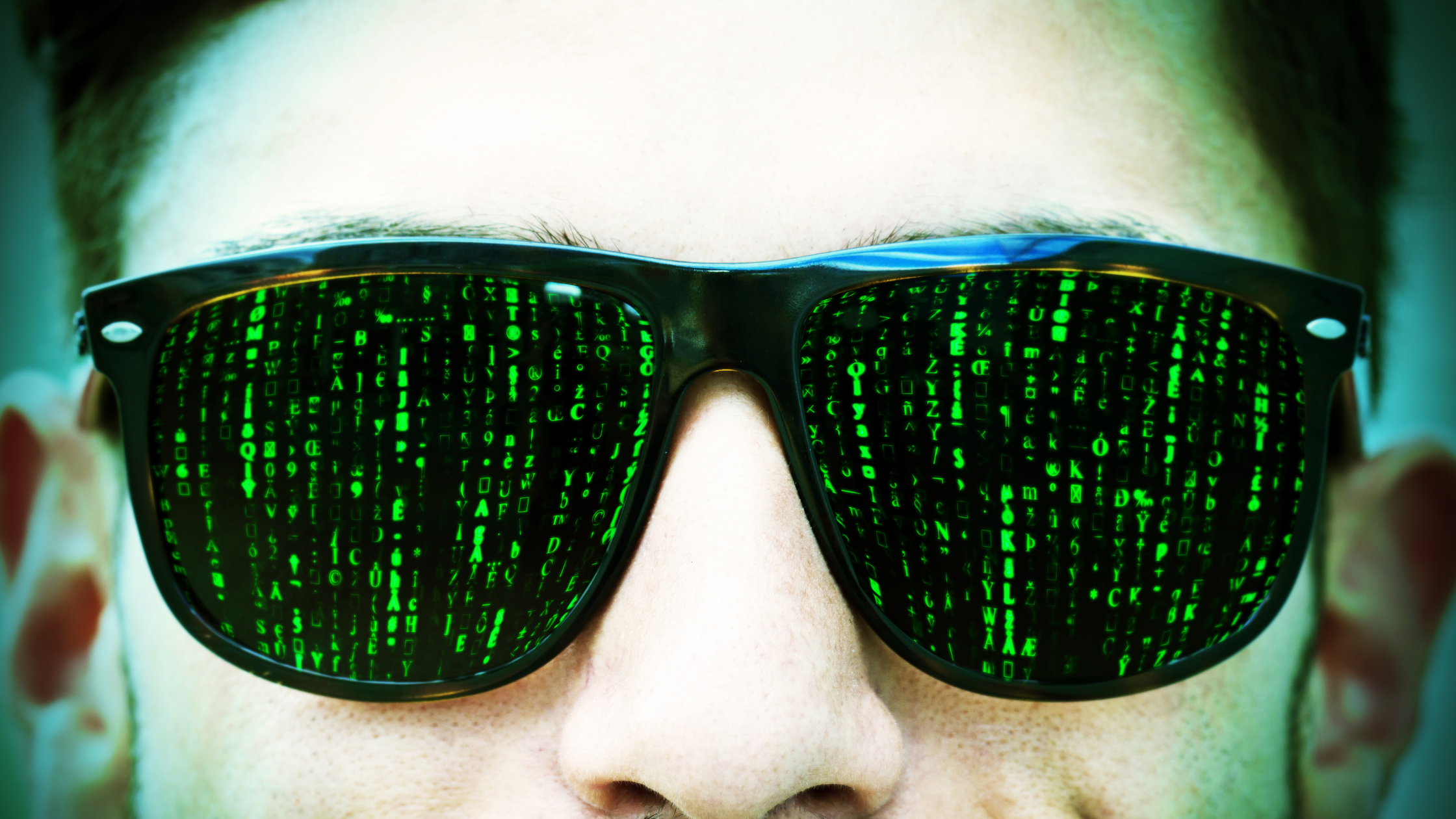 man's eyes covered in sunglasses with green matrix code in lenses