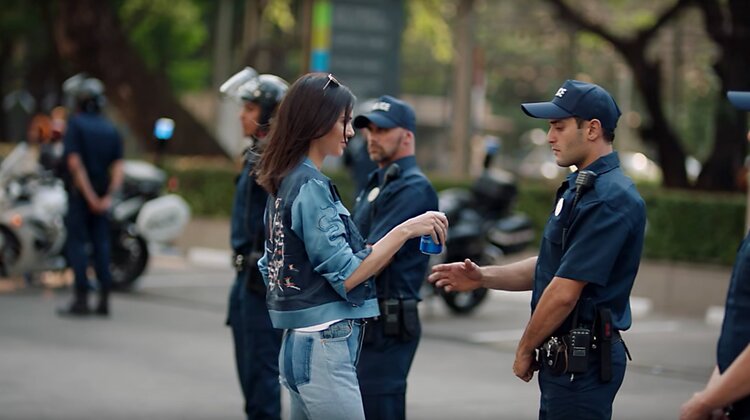 Woman handing a drink to a police officer