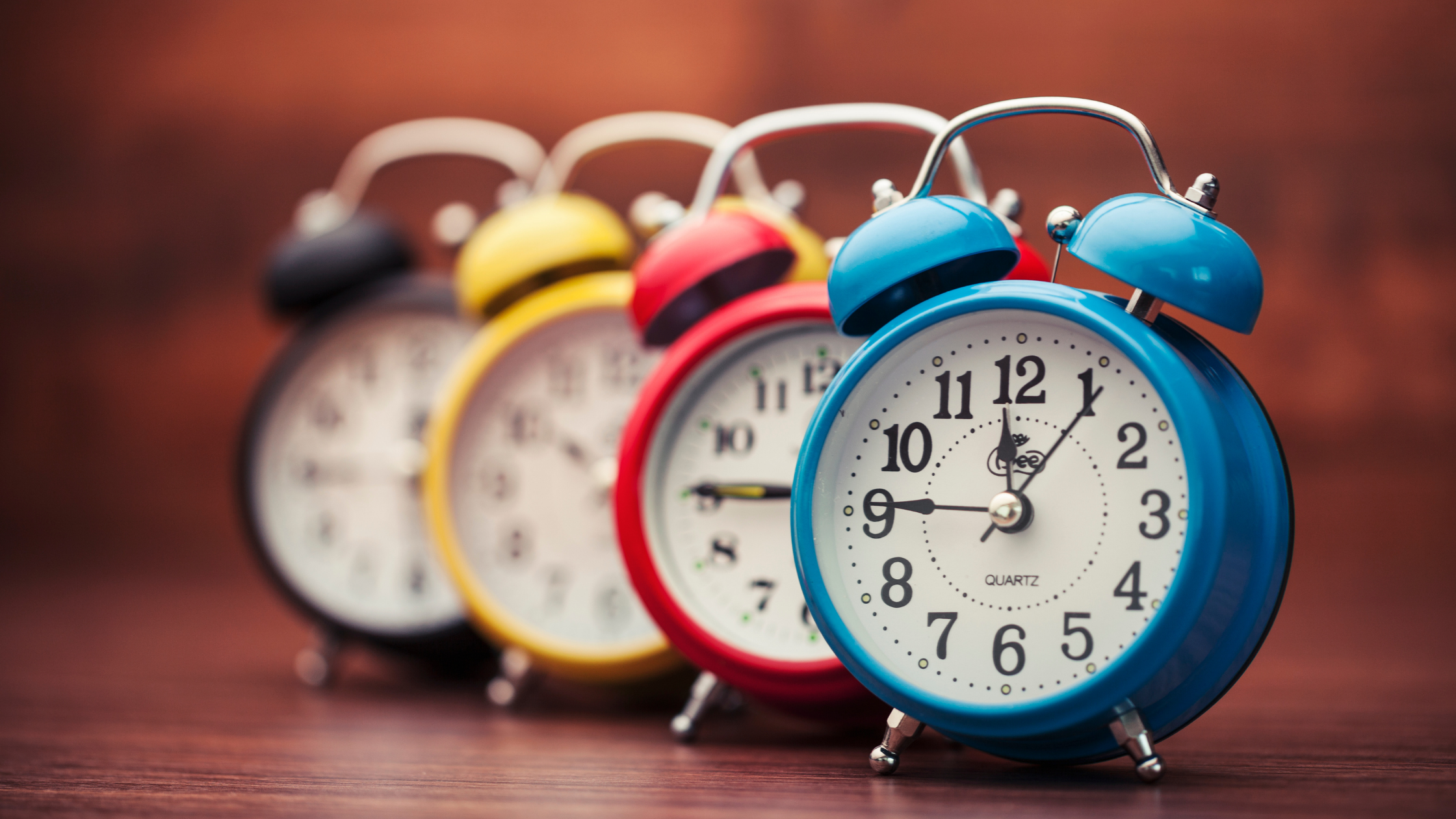 line of colorful alarm clocks